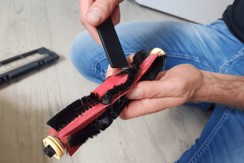 Haare werden mit dem Reinigungswerkzeug von der Bürste entfernt